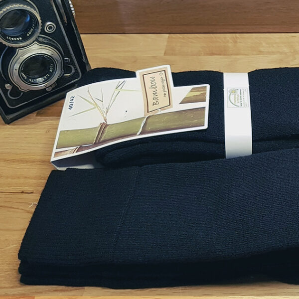 Des chaussettes en bambou et coton bio épaisses longue à coté d'un appareil photo vintage